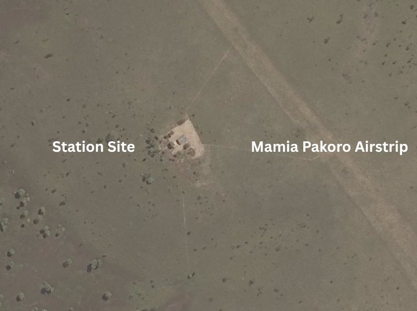 An annotated satellite photo of a remote savanna in Suriname. A text label points to a faint dirt airstrip labeled 'Mamia Pakoro Airstrip.' Another label points to a small, cleared area with a structure, labeled 'Station Site. An annotated satellite photo of a remote savanna in Suriname. A text label points to a faint dirt airstrip labeled 'Mamia Pakoro Airstrip.' Another label points to a small, cleared area with a structure, labeled 'Station Site.